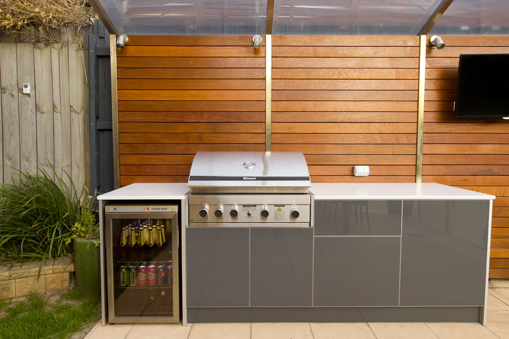 Imagen de patio actual en patio trasero con cocina exterior, adoquines de hormigón y toldo