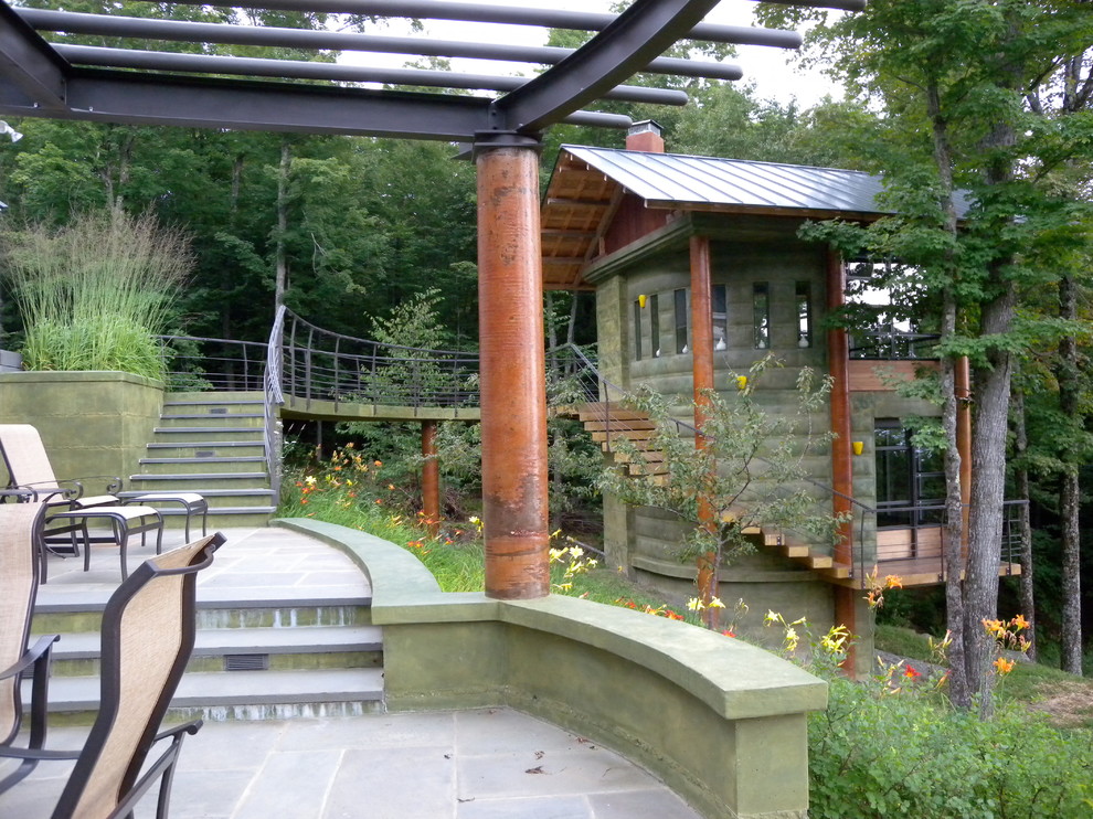 Example of a large mountain style backyard concrete paver patio design in Burlington with a pergola