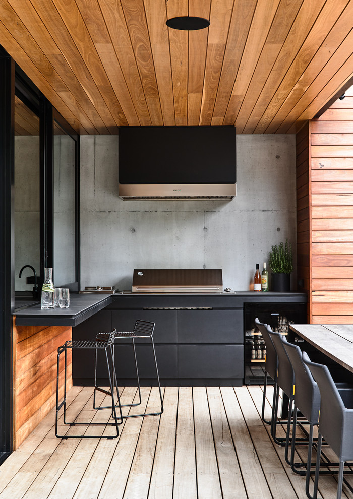 Aménagement d'une terrasse en bois contemporaine avec une cuisine d'été et une extension de toiture.