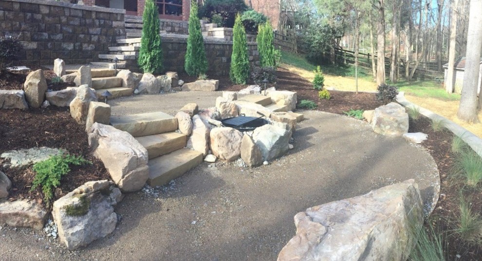 Photo of a large rustic back patio in Charlotte with a fire feature and natural stone paving.