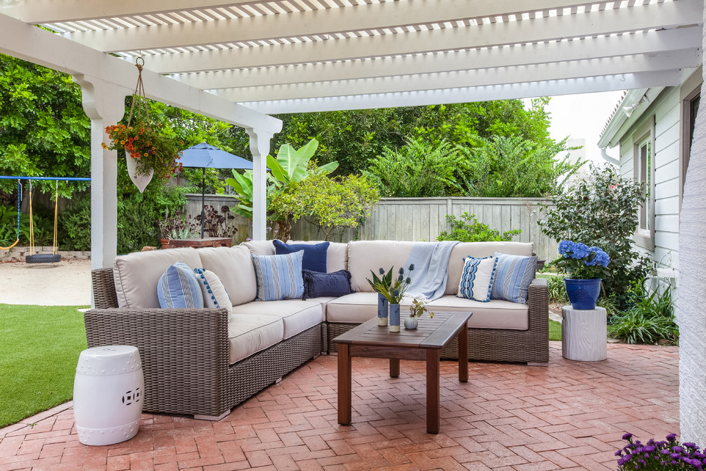 Example of a beach style backyard brick patio design in San Diego with a pergola
