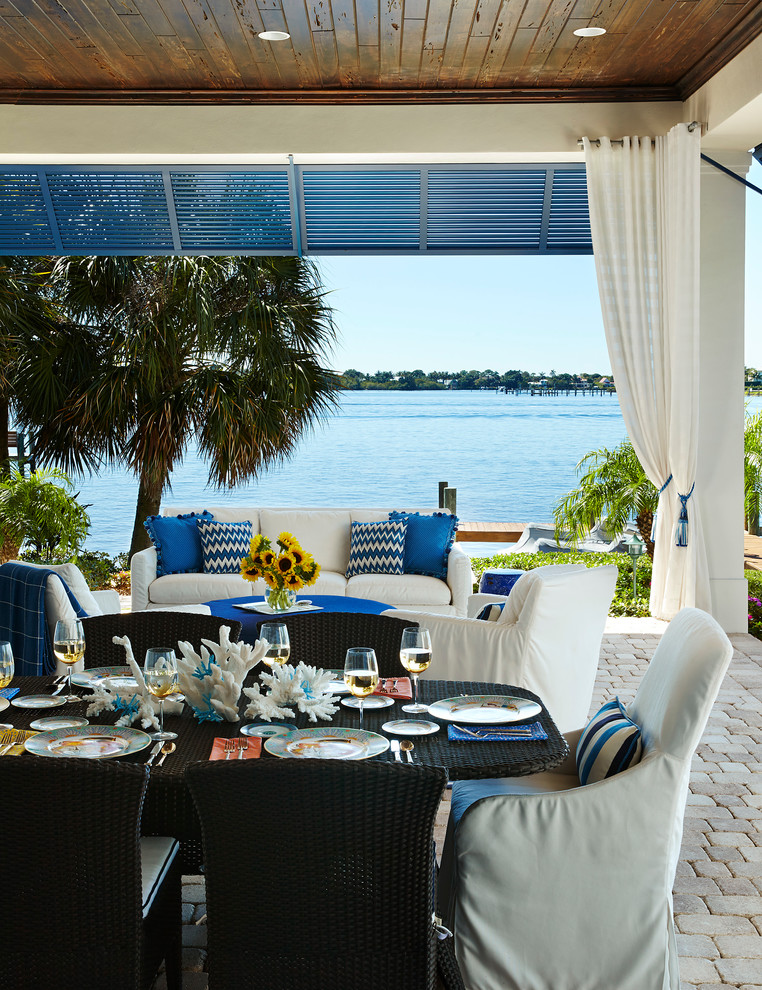 Cette photo montre une terrasse arrière bord de mer de taille moyenne avec une extension de toiture et des pavés en béton.