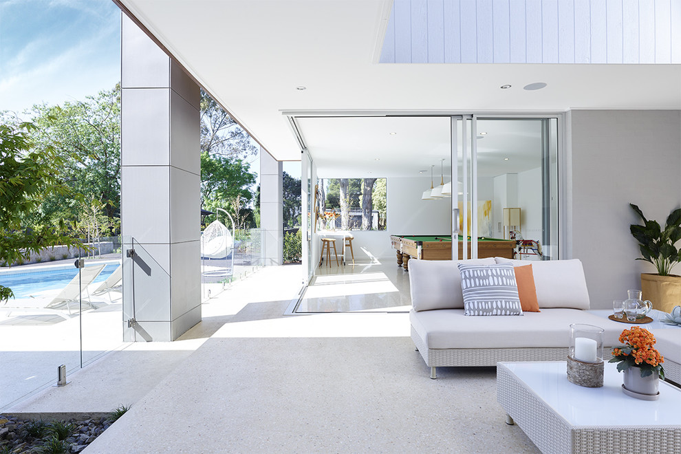 This is an example of a large contemporary back patio in Melbourne with concrete slabs and a roof extension.