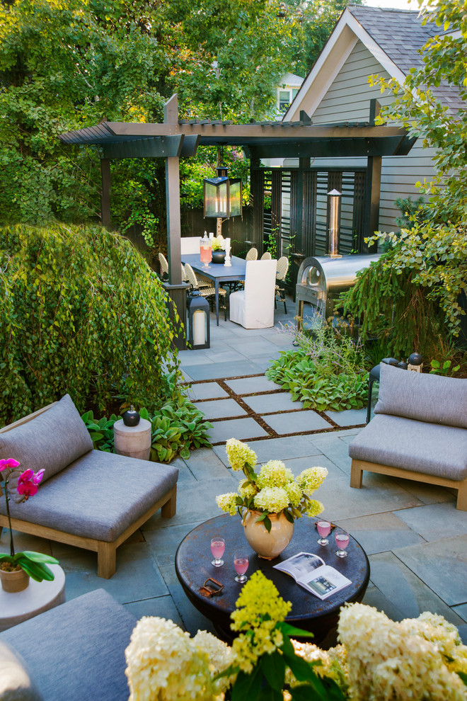 Small contemporary back patio in Chicago with natural stone paving and a pergola.