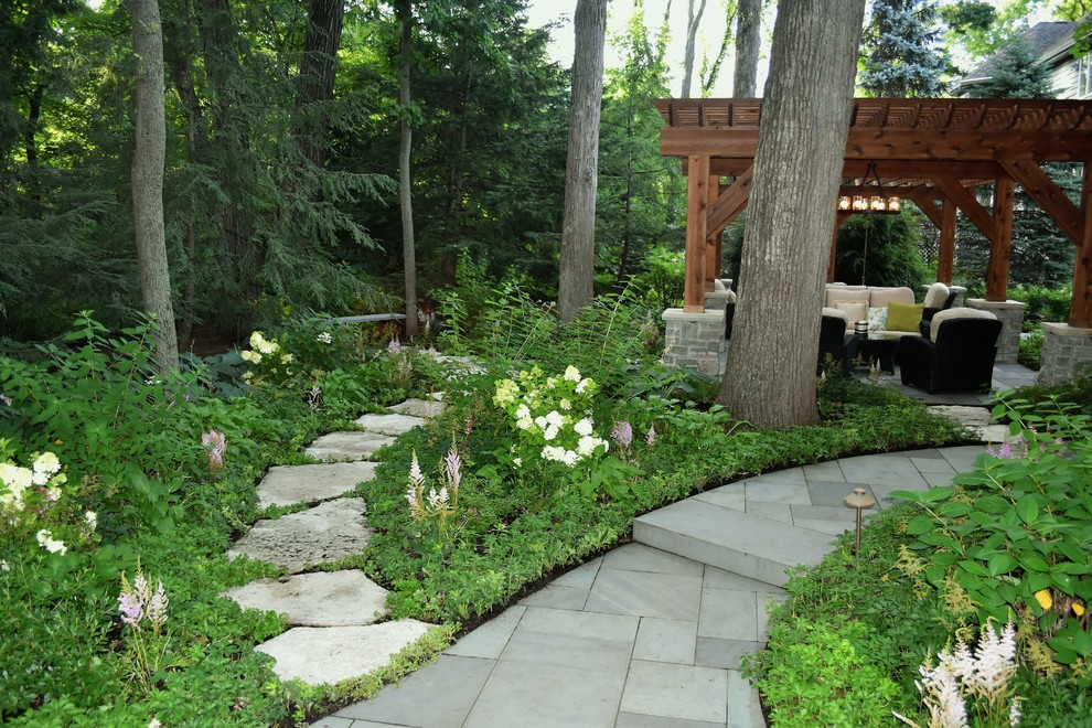 Imagen de patio tradicional en patio trasero con adoquines de piedra natural y pérgola