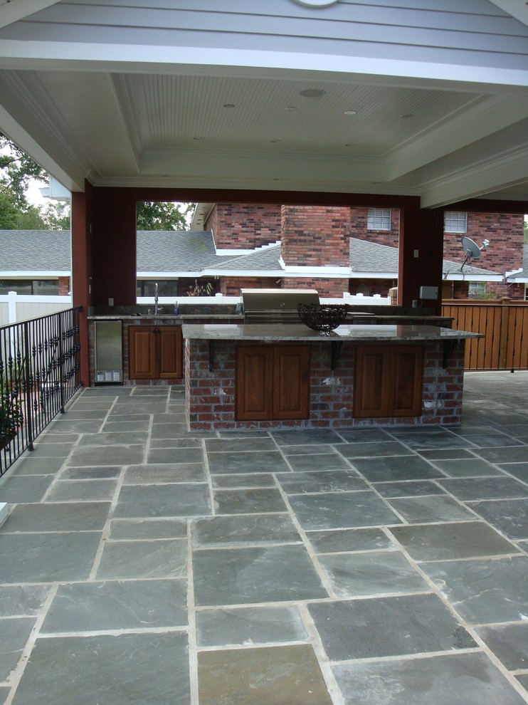 Immagine di un grande patio o portico tradizionale dietro casa con pavimentazioni in pietra naturale e un tetto a sbalzo