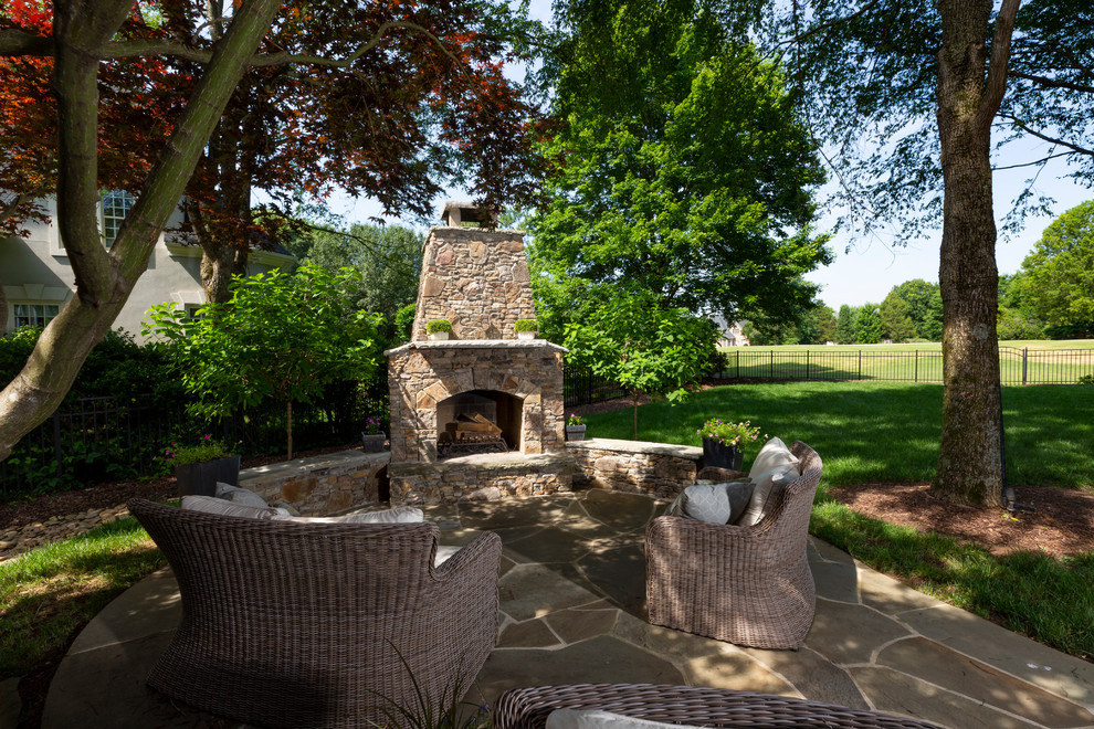Example of a mid-sized classic backyard stone patio design in Charlotte with a fireplace and no cover