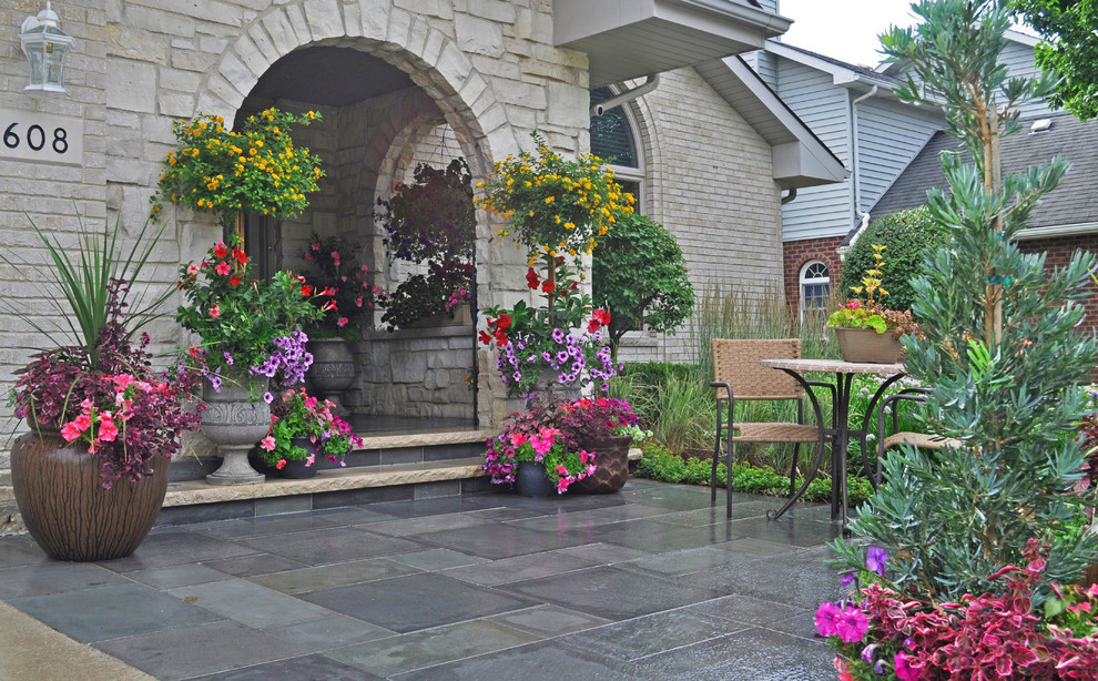Стильный дизайн: маленький двор на переднем дворе в стиле неоклассика (современная классика) с растениями в контейнерах, покрытием из каменной брусчатки и навесом для на участке и в саду - последний тренд
