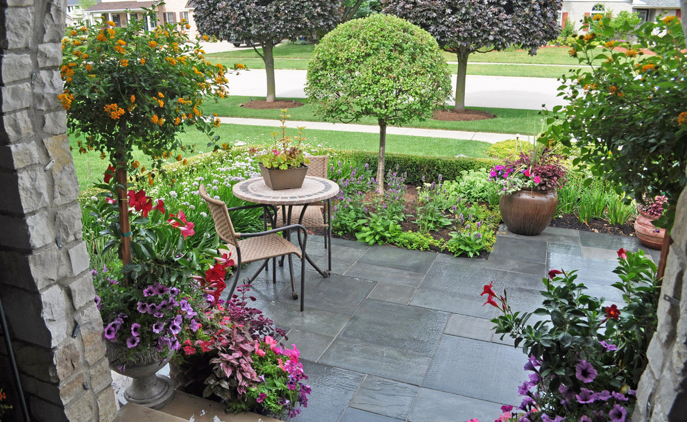 Ispirazione per un piccolo patio o portico contemporaneo davanti casa con un giardino in vaso, pavimentazioni in pietra naturale e un tetto a sbalzo