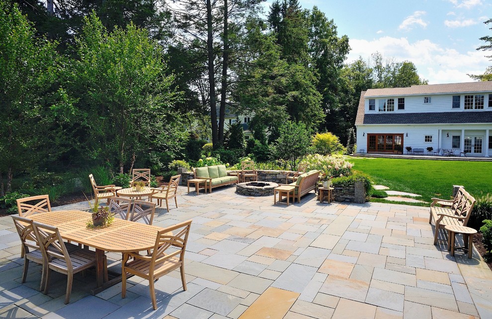 Example of a large classic backyard stone patio design in Boston with a fire pit and no cover