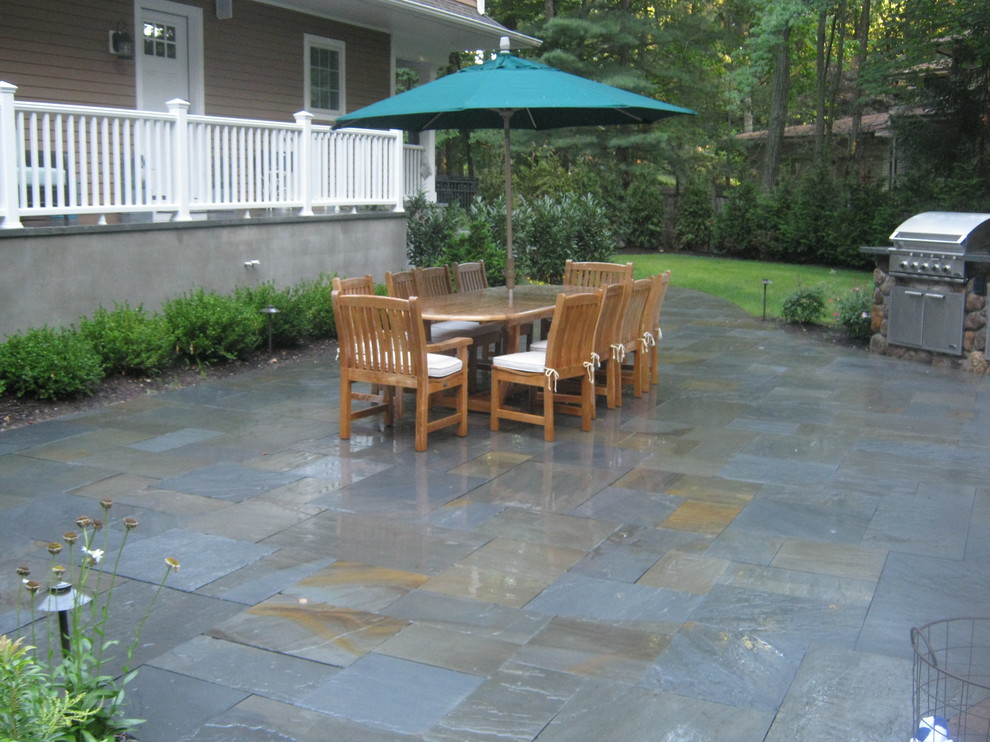 This is an example of a large classic back patio in New York with an outdoor kitchen and tiled flooring.