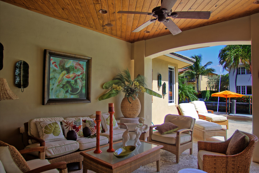 Foto di un patio o portico tropicale dietro casa con lastre di cemento e un tetto a sbalzo