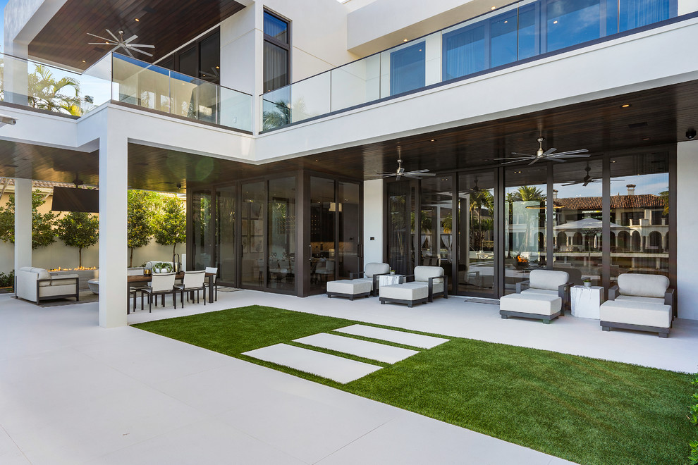 Inspiration for a large modern backyard tile patio remodel in Miami with a fire pit and a roof extension