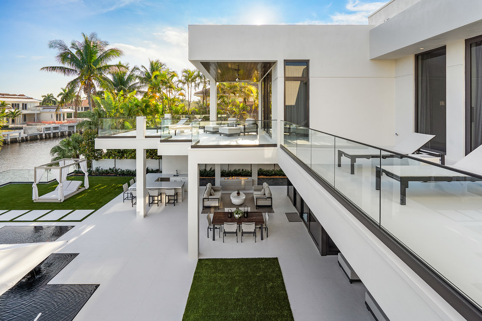 Photo of a large modern back patio in Miami with an outdoor kitchen, tiled flooring and a roof extension.