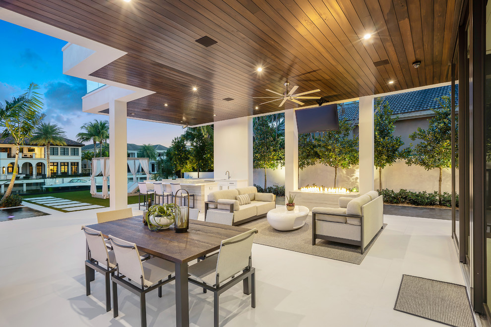 Inspiration for a large modern back patio in Miami with an outdoor kitchen, tiled flooring and a roof extension.