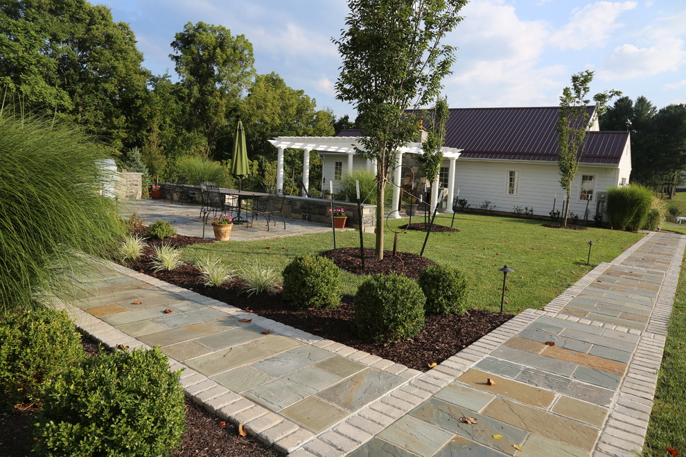 Immagine di un grande patio o portico dietro casa con pavimentazioni in pietra naturale