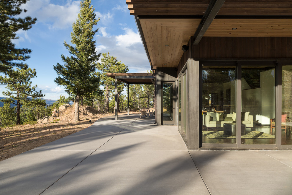 Inspiration for a large contemporary side patio in Denver with concrete slabs and a roof extension.