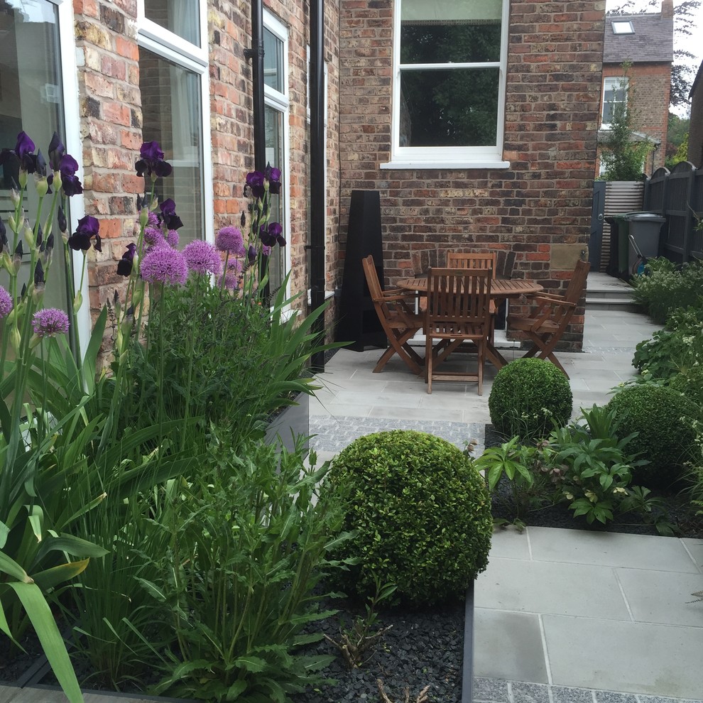 Immagine di un piccolo patio o portico design in cortile con un giardino in vaso e pavimentazioni in pietra naturale