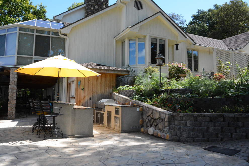 Cette image montre une terrasse arrière traditionnelle de taille moyenne avec une cuisine d'été et des pavés en pierre naturelle.