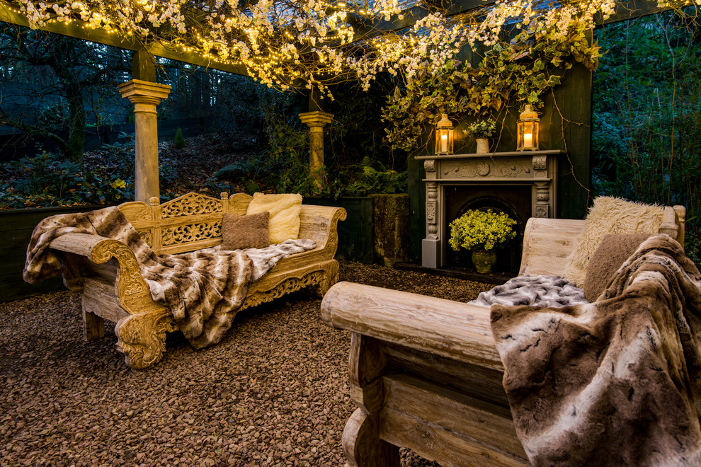 Ejemplo de patio romántico de tamaño medio en patio trasero con gravilla, brasero y pérgola