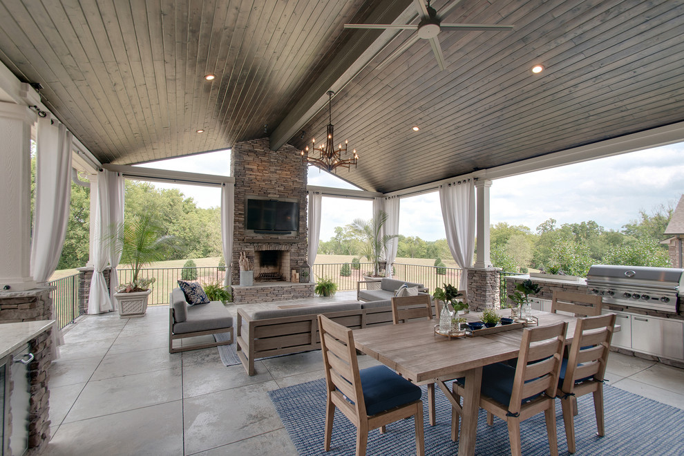Exemple d'une grande terrasse arrière rétro avec une cuisine d'été, une dalle de béton et une extension de toiture.