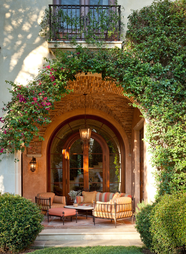 Example of a tuscan patio design in Orange County with a roof extension