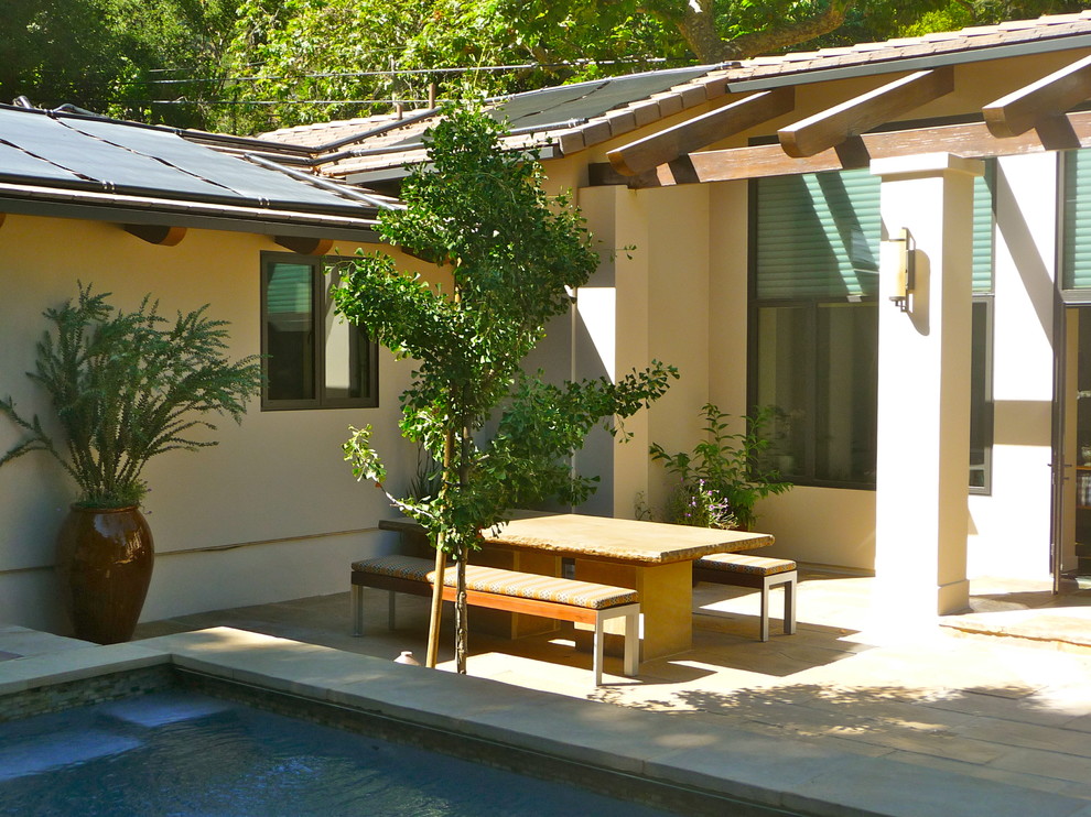Inspiration pour une terrasse arrière vintage de taille moyenne avec des pavés en béton et une extension de toiture.
