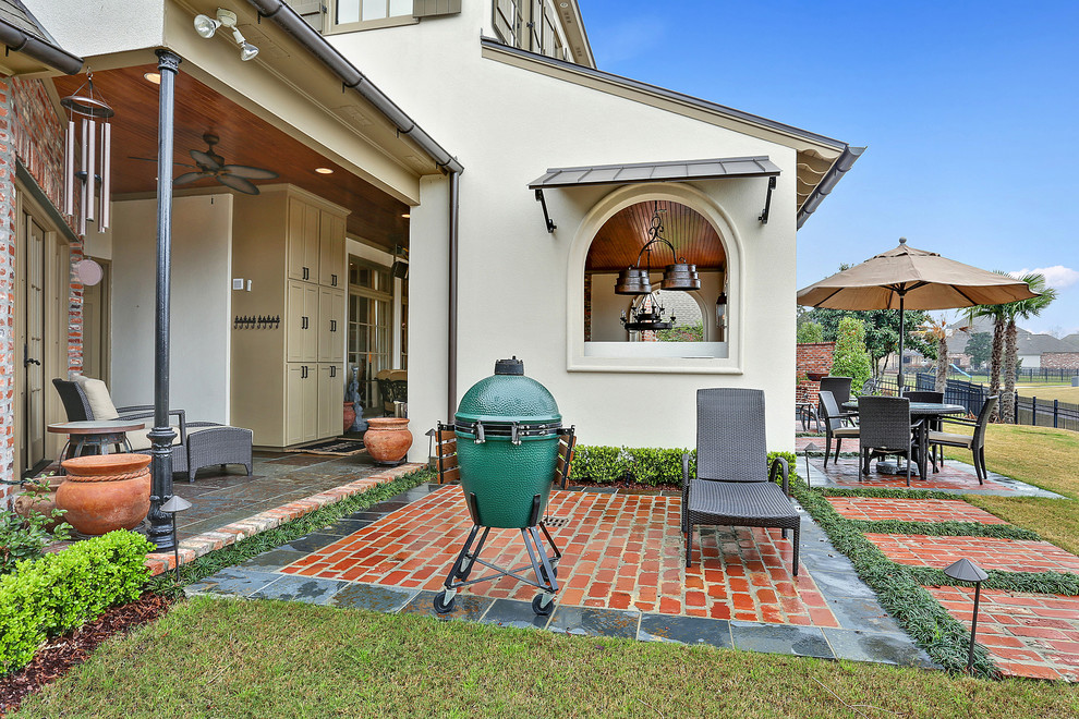 Großer, Überdachter Klassischer Patio hinter dem Haus mit Outdoor-Küche und Natursteinplatten in New Orleans