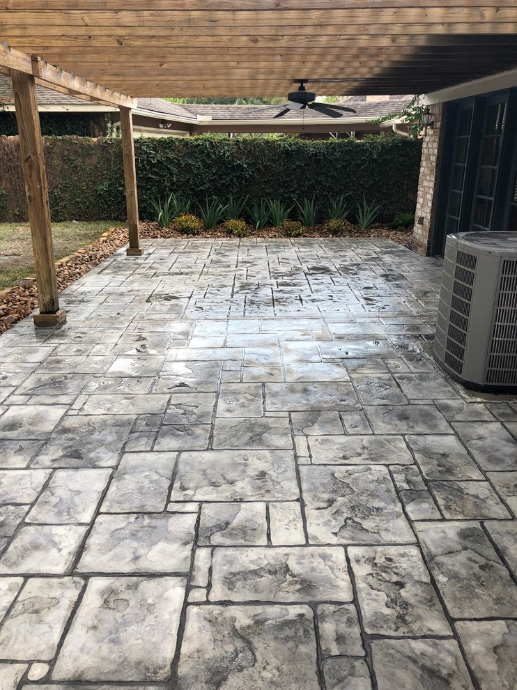 Large eclectic backyard stamped concrete patio photo in Houston with a pergola