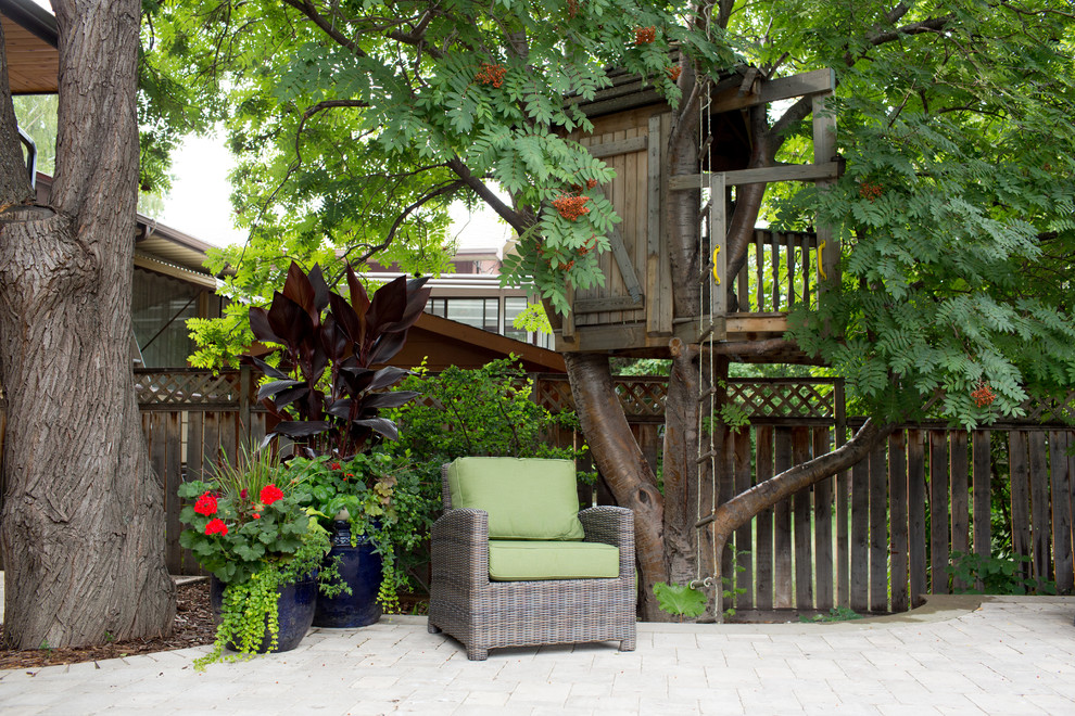 Photo of a medium sized rustic back patio in Calgary with natural stone paving and fencing.