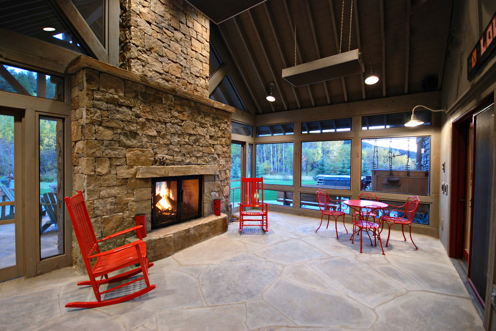 Esempio di un patio o portico country di medie dimensioni e dietro casa con un focolare, lastre di cemento e un tetto a sbalzo
