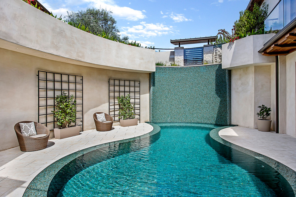 Foto di una grande piscina design personalizzata in cortile con pavimentazioni in pietra naturale