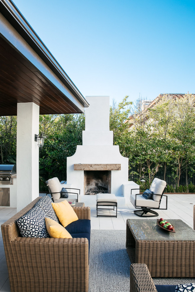 Réalisation d'une grande terrasse arrière minimaliste avec une cheminée, des pavés en béton et un gazebo ou pavillon.