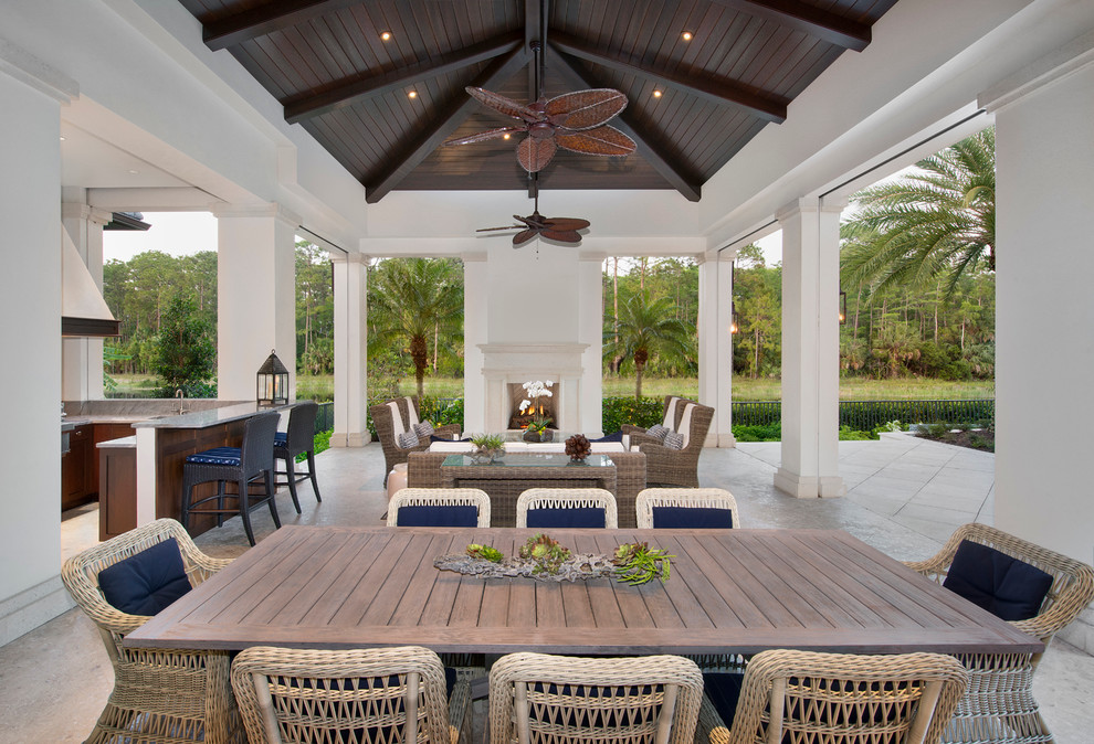 Immagine di un ampio patio o portico tropicale dietro casa con pavimentazioni in pietra naturale e un tetto a sbalzo