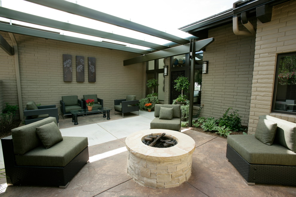 Esempio di un patio o portico contemporaneo di medie dimensioni e dietro casa con un focolare, lastre di cemento e una pergola