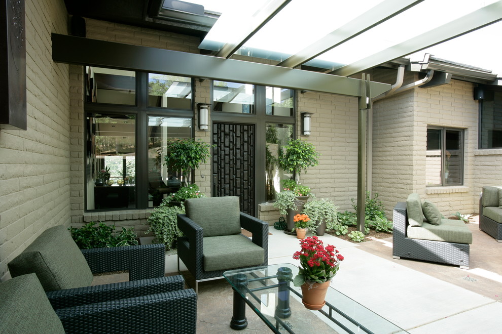 Ispirazione per un patio o portico minimal di medie dimensioni e dietro casa con un focolare, lastre di cemento e una pergola