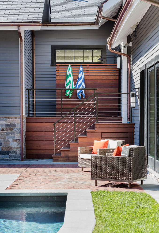 Стильный дизайн: большой двор на заднем дворе в современном стиле с летним душем, мощением клинкерной брусчаткой и навесом - последний тренд
