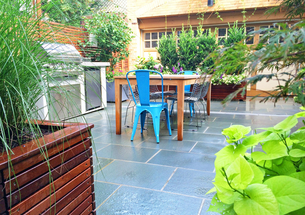Exemple d'une terrasse avec des plantes en pots arrière tendance avec des pavés en pierre naturelle.
