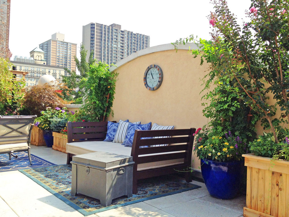 Cette image montre une terrasse avec des plantes en pots bohème avec des pavés en béton.