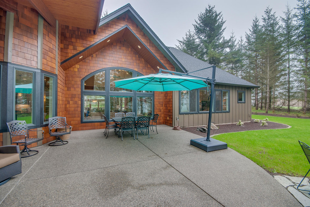 This is an example of a large classic back patio in Portland with concrete slabs.
