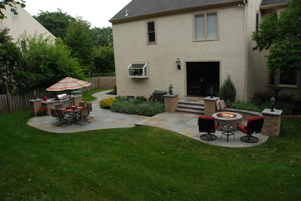 Foto di un piccolo patio o portico classico dietro casa con un focolare, pavimentazioni in pietra naturale e nessuna copertura