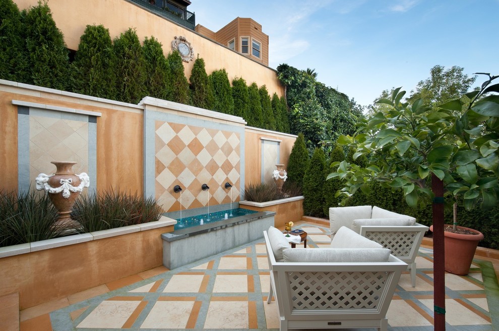 Пример оригинального дизайна: двор в средиземноморском стиле с фонтаном и покрытием из плитки без защиты от солнца