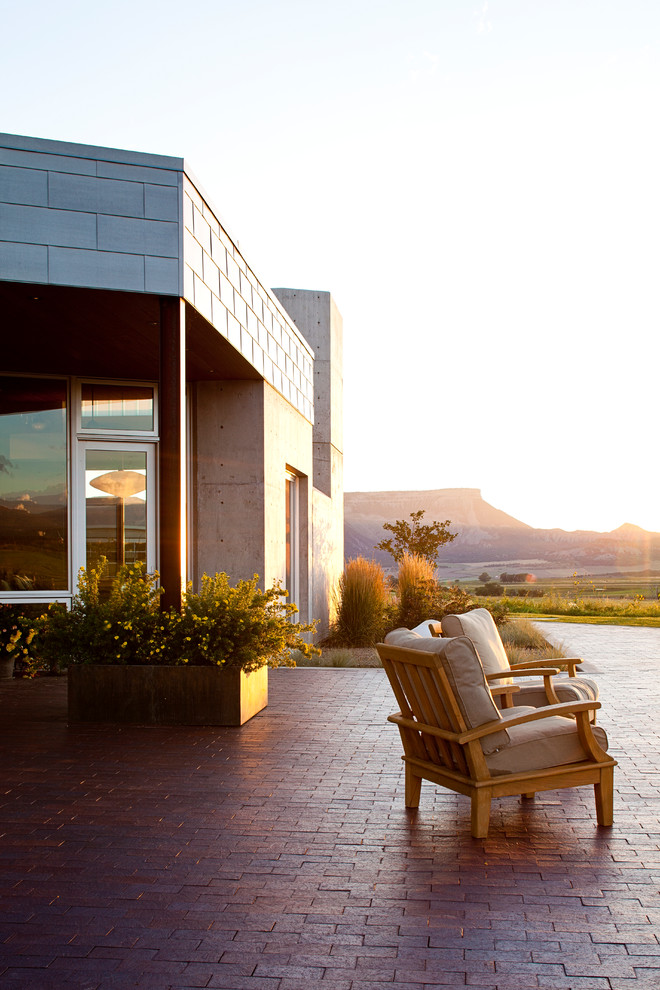 Cette image montre une grande terrasse minimaliste avec des pavés en brique.