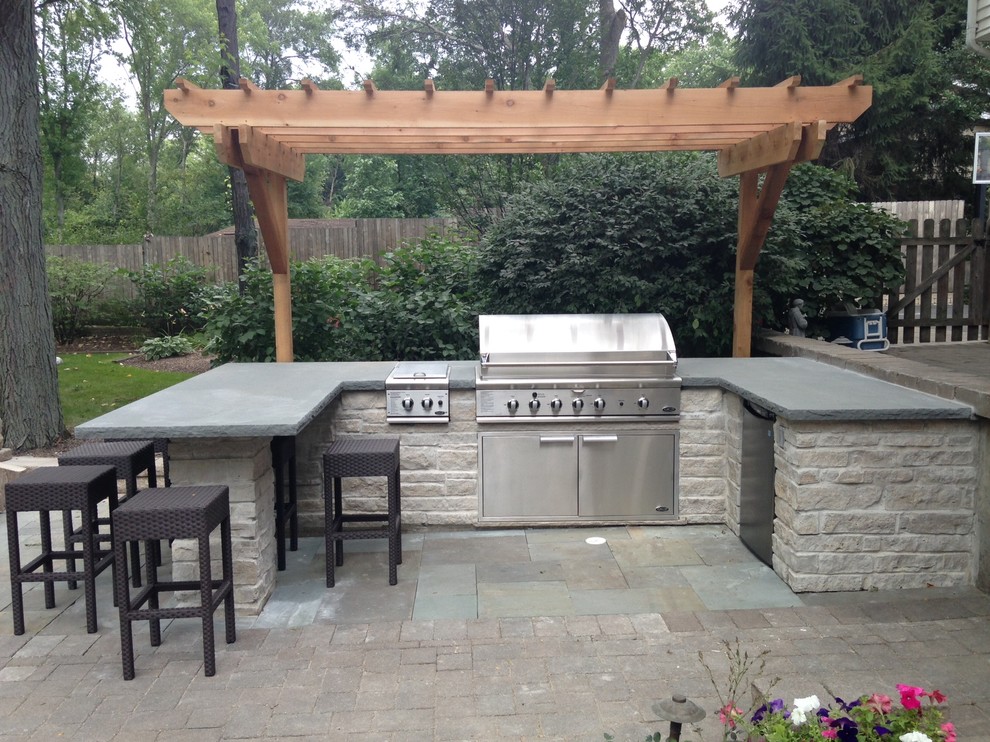 Medium sized contemporary back patio in Chicago with an outdoor kitchen, natural stone paving and a pergola.