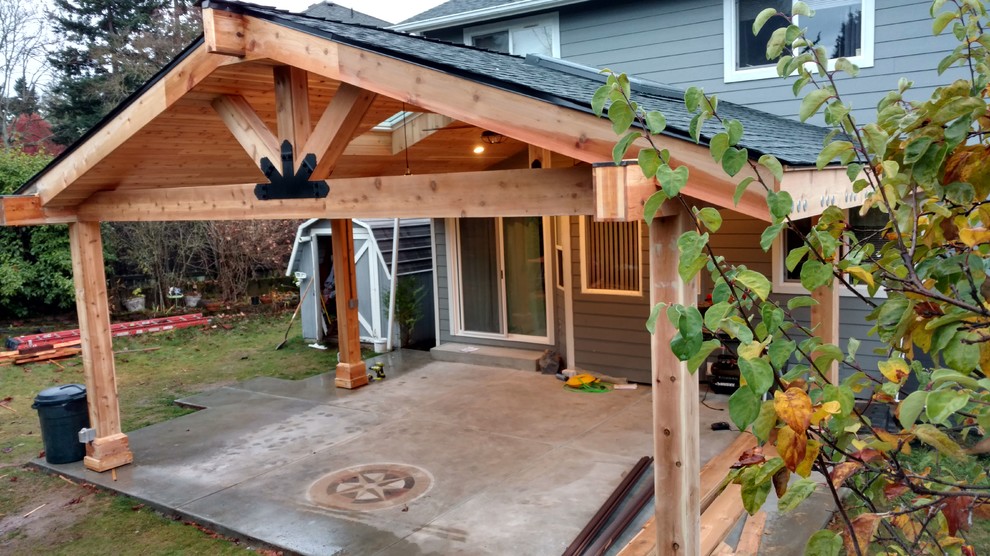 Immagine di un ampio patio o portico chic dietro casa con piastrelle e un tetto a sbalzo