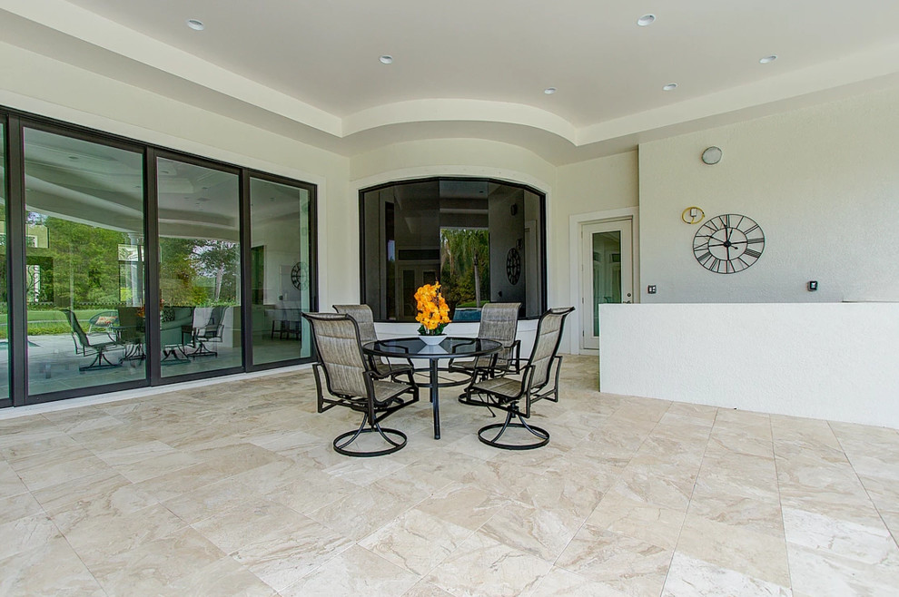 Photo of a large traditional back patio in Miami with tiled flooring and a roof extension.