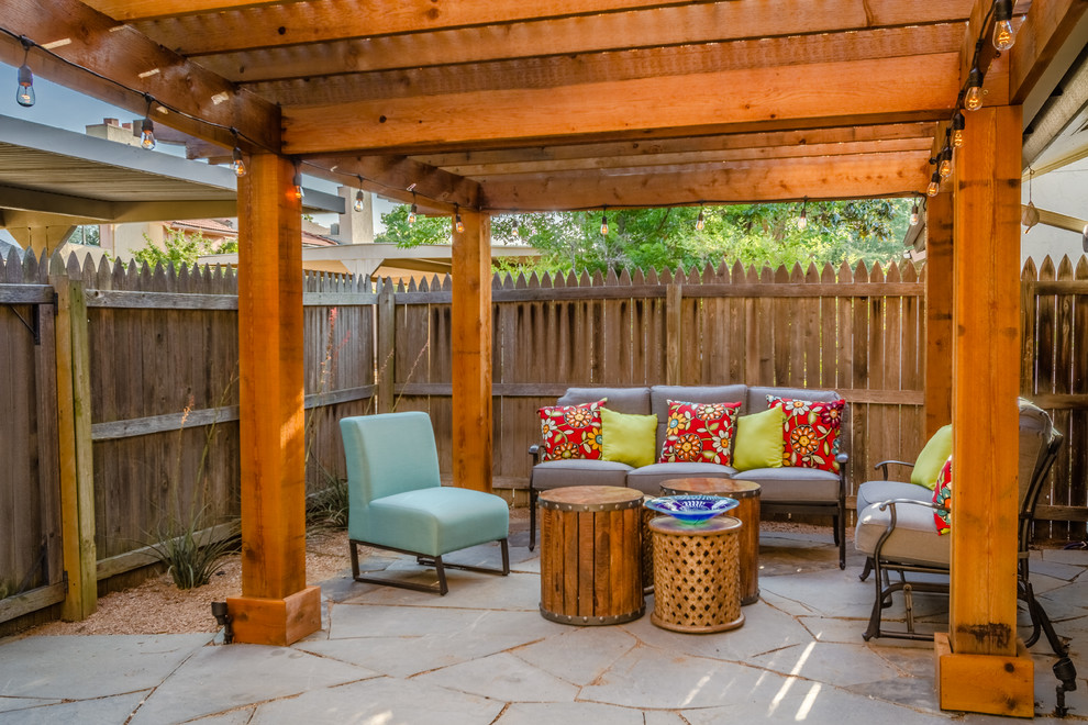 Mid-sized southwest backyard stone patio photo in Dallas with a pergola