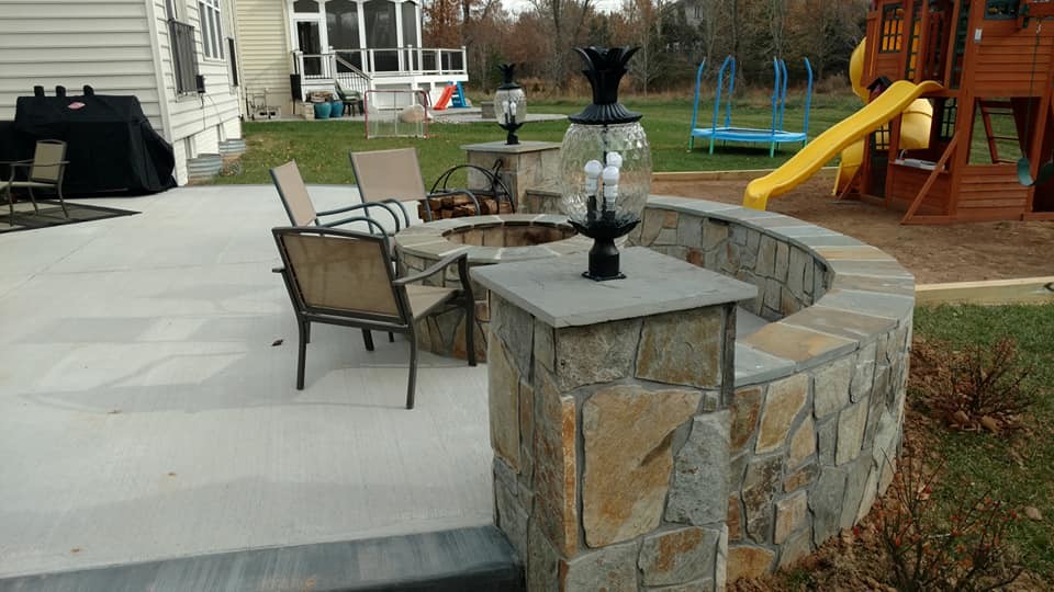 This is an example of a large classic back patio in Other with a fire feature, natural stone paving and no cover.