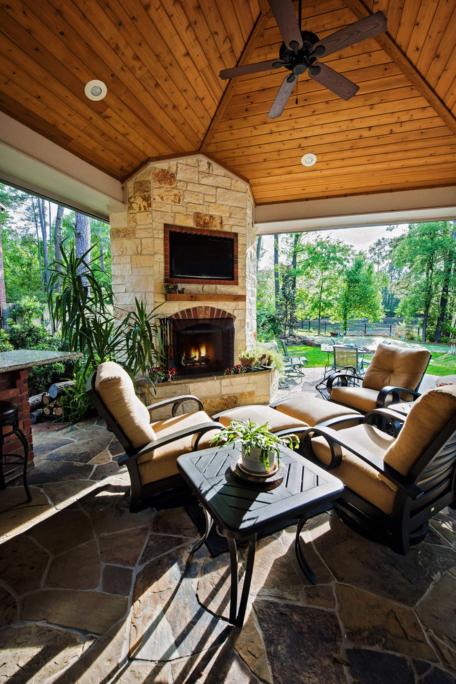Inspiration for a large timeless backyard stone patio remodel in Houston with a fire pit and a roof extension