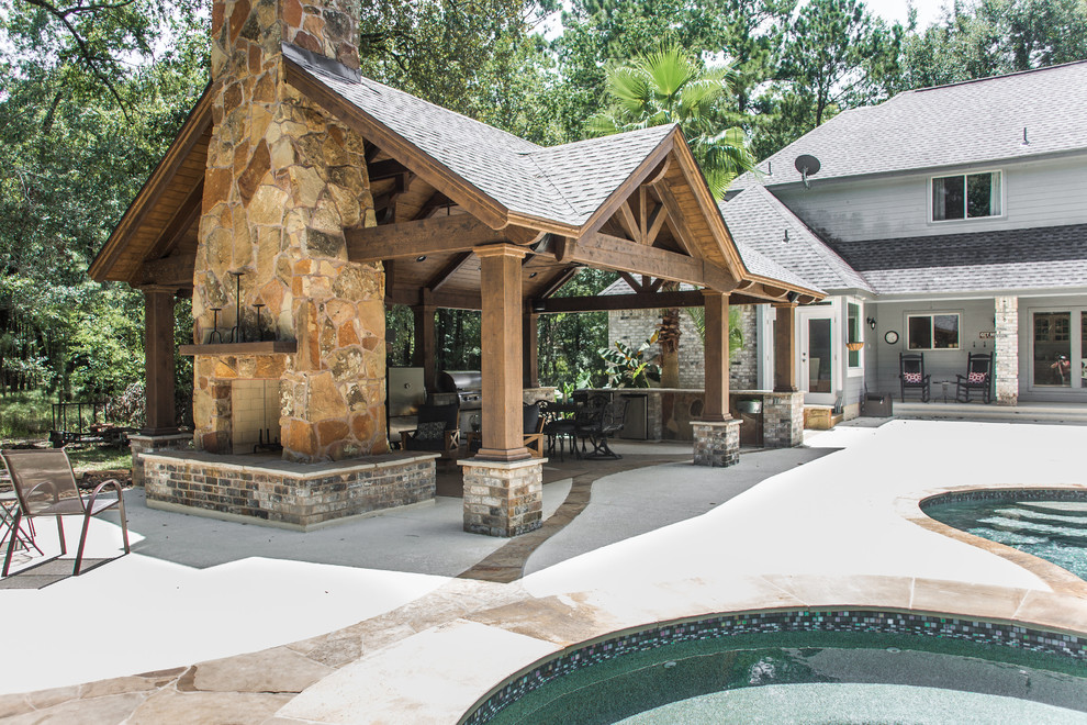Example of a large country backyard stone patio design in Houston with a fire pit and a gazebo
